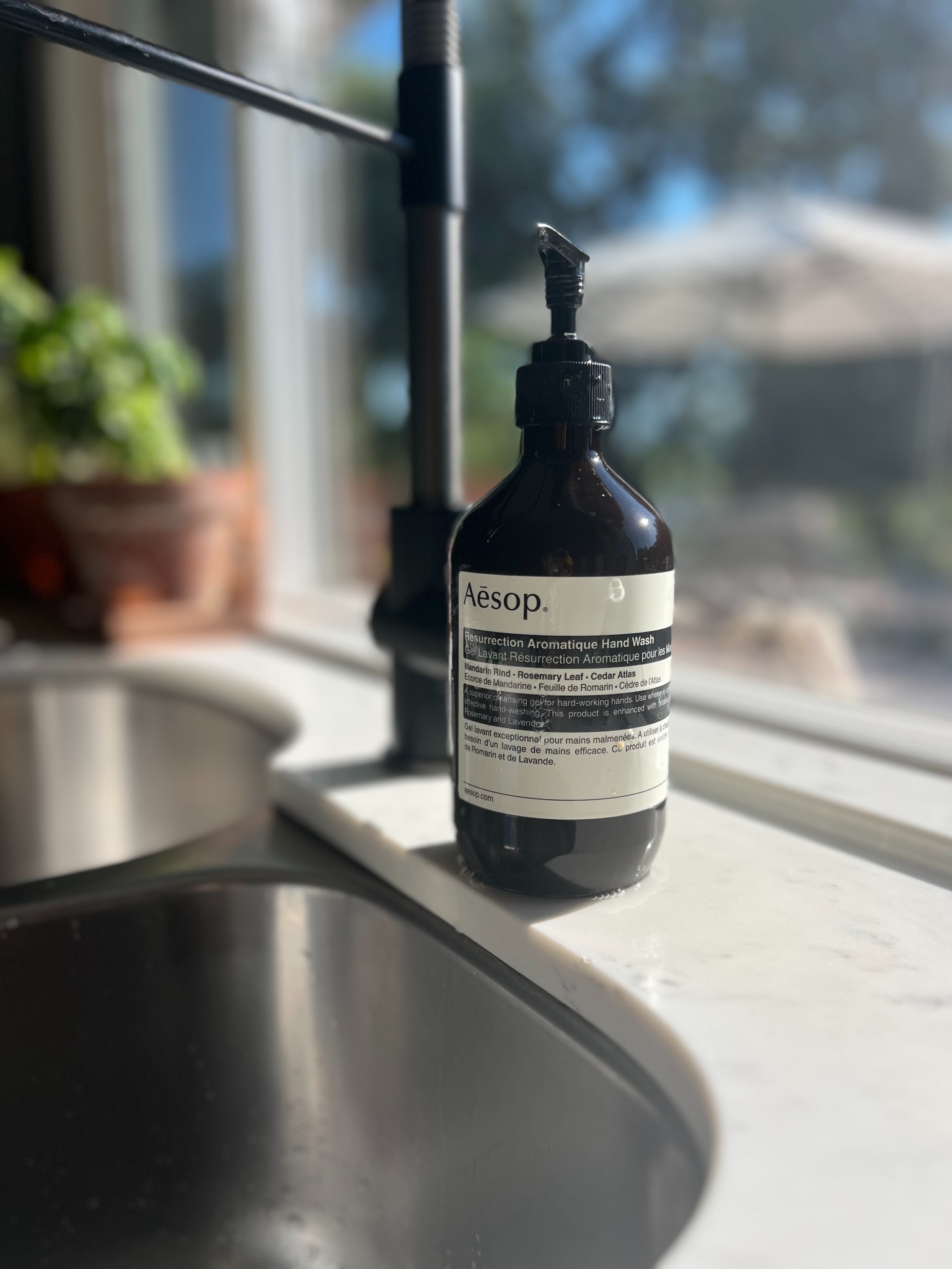 Aesop Resurrection Aromatique Hand Wash beside a sunlit kitchen sink